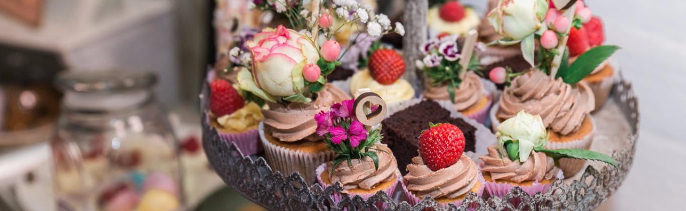 Etagere mit dekorierten Cupcakes, Blüten und Erdbeeren