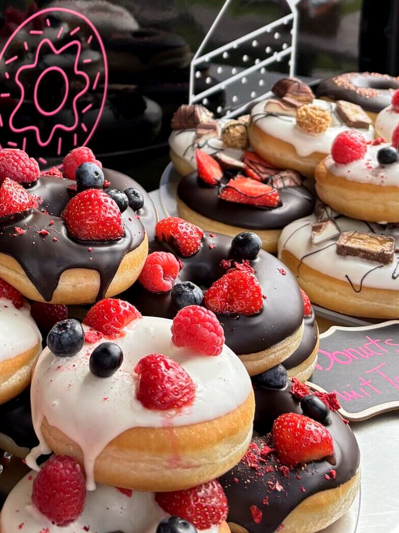 Donuts mit Beeren und Schokolade in der Auslage des Wagens.