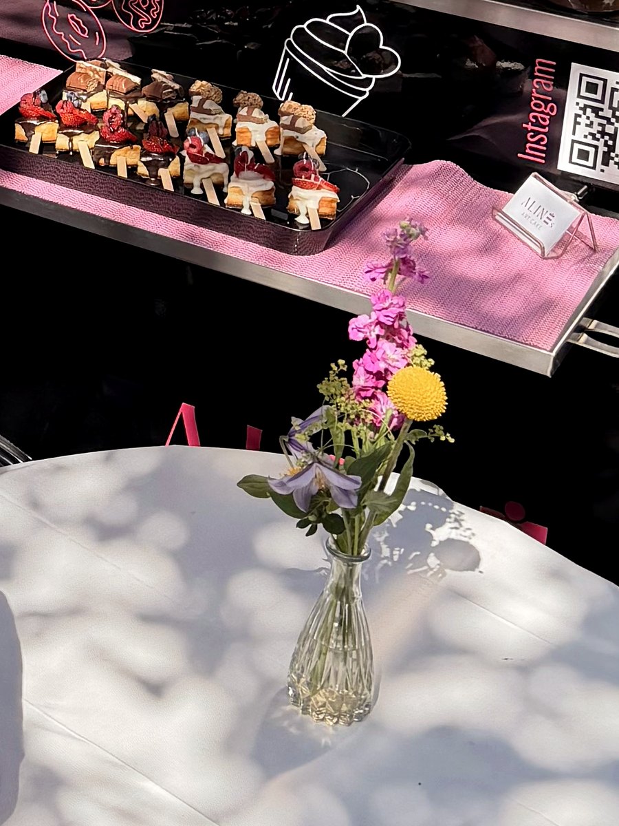 Stehtisch mit Blumen vor der Auslage des Wagens.